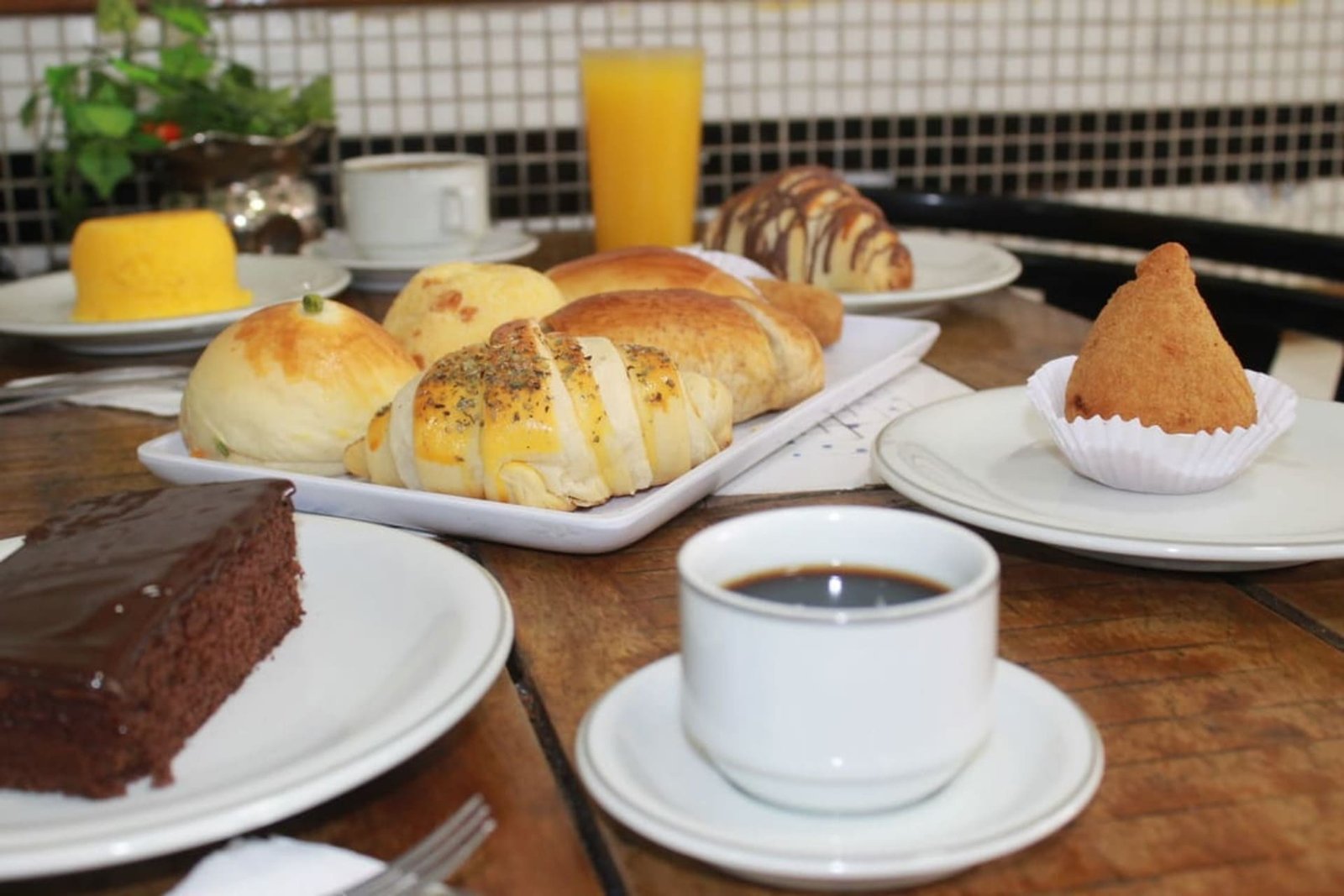 Mesa de café da manhã da Casa do Pão, com café, pães, salgados e bolo